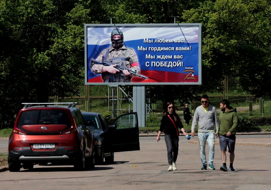 People walk near a banner in support of the Russian Army, in the town of Vyborg, Leningrad Region