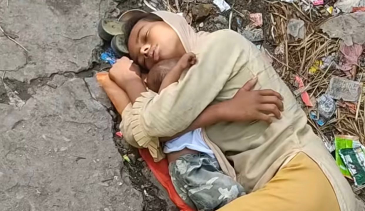 A mother takes care of herself among the garbage on the sidewalk.       Photo: Social Media 