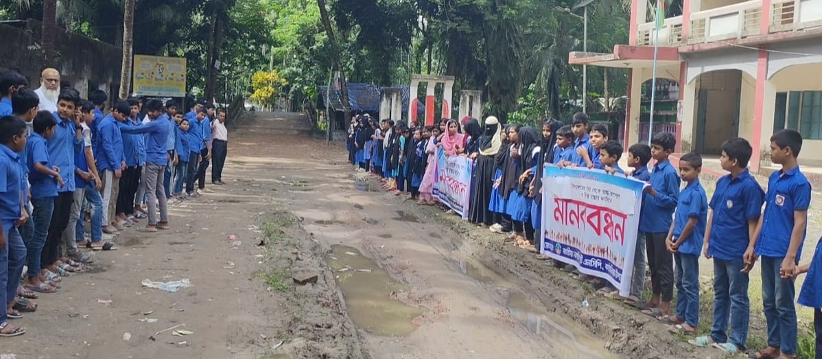 Students, teachers, and local residents form a human chain in front of Shauljalia High School in Kathalia, Jhalokathi, demanding the removal of a road being built through their shared school playground on Thursday morning.