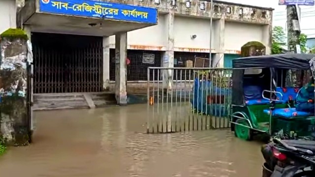 Floodwaters inundate the road in front of the Sub-Registry Office in Kathalia Upazila, disrupting daily activities and transportation.