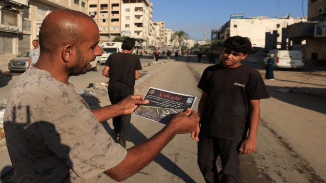 A Palestinian man reads an Israeli leaflet ordering residents to evacuate Gaza City, amid ongoing bombardment and preparations for a major offensive, September 9, 2025. REUTERS/…