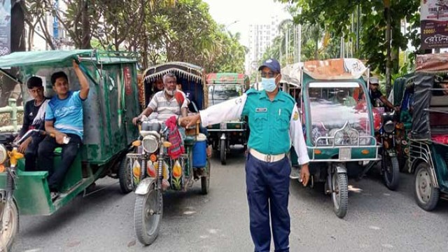 Traffic constable Zahurul Islam directs vehicles manually at Dhorikharbona Mor in Rajshahi as traffic signal lights remain nonfunctional.