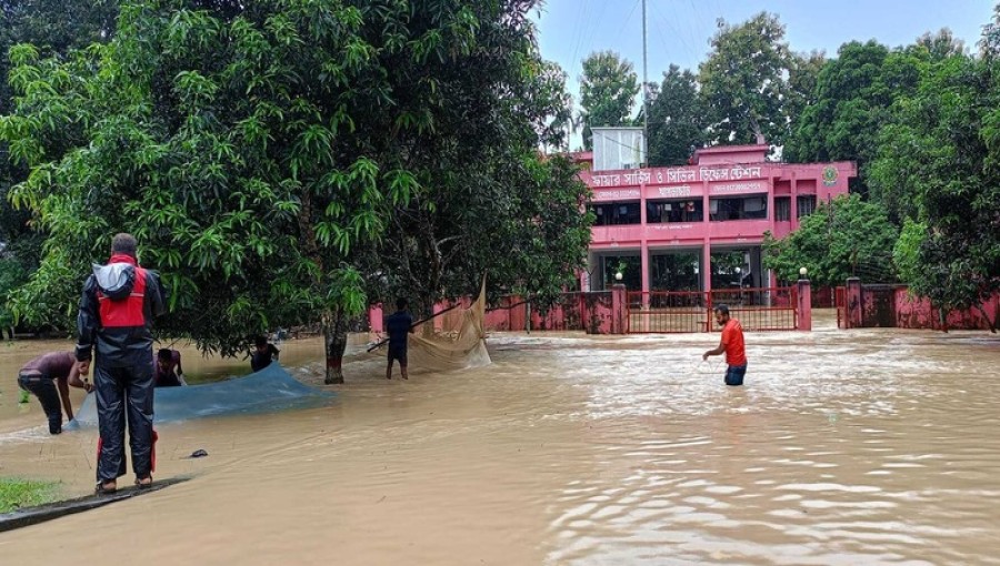 Residents navigate through floodwaters in Khagrachari as heavy rains have submerged low-lying areas, trapping over 500 families and increasing the risk of landslides. Photo: Voice7 News