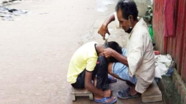 "A traditional barber in rural Bengal tends to a customer on a wooden stool, preserving a vanishing legacy amidst the rise of modern salons."