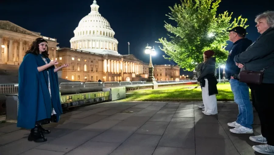 Tourists gather under the full moon as actress Victoria Sova portrays Anna Surratt, sharing chilling tales of Washington, D.C.'s haunted history.