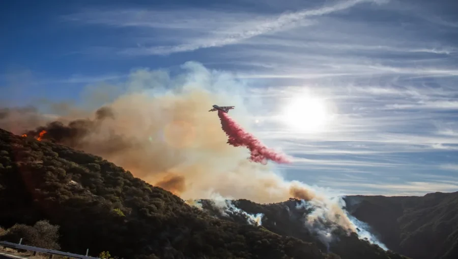 A firefighter aircraft releases fire retardant as the Franklin Fire burns near Malibu, California on December 10, 2024. The wildfire has scorched over 2800 acres, causing evacuations and destroying homes.