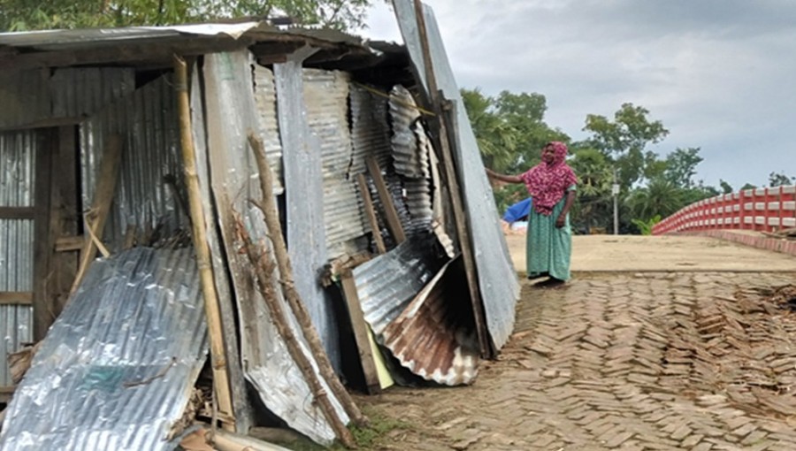 Fokhru Nessa, 50, with her family, sits beside their makeshift shelter on a bridge in Feni. The devastating floods destroyed their home and property, forcing them to live in this temporary refuge. Photo: V7N