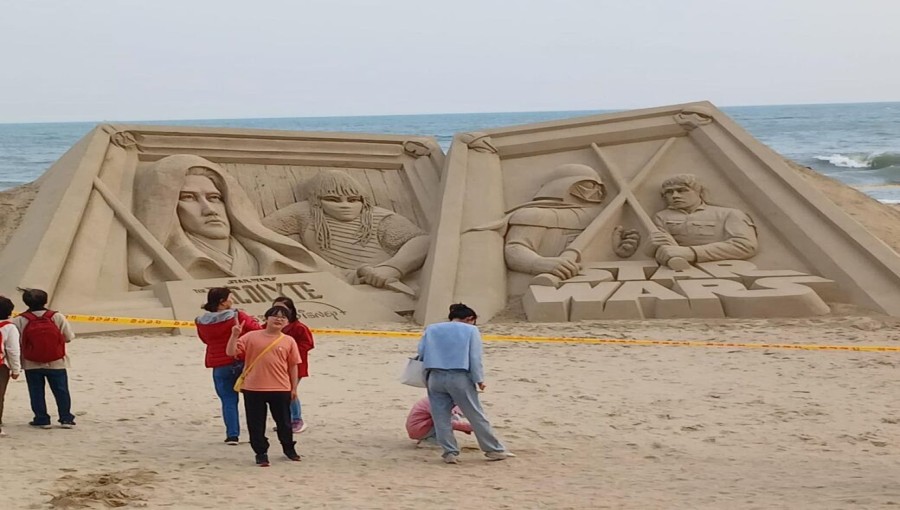 Visitors take pictures of a Star Wars-themed sand sculpture at Haeundae Beach in Busan on Monday