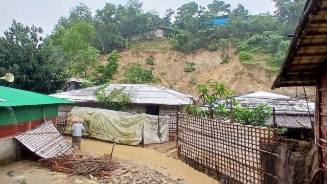 Rohingya refugee wades through floodwaters inside a camp in Ukhiya after days of heavy rain submerged shelters and triggered landslides, damaging hundreds of homes. (Photo: V7N)