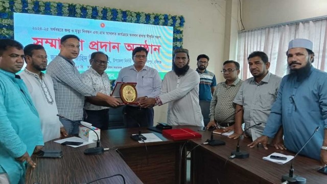 UNO Md. Zahid Bin Kashem hands over a crest to a top performer during the award ceremony in Madhabpur Upazila.