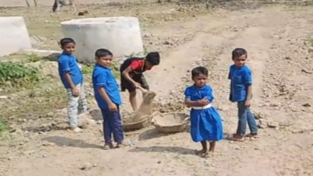 Young students at Ganganagar Nirad Chandra Government Primary School in Netrokona dig soil from a nearby area while teachers stand nearby on February 17.