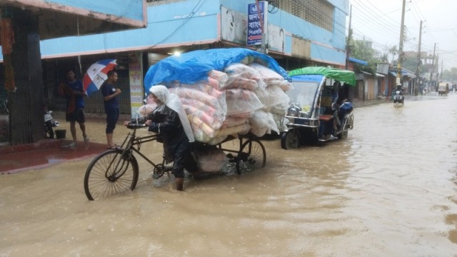 A van driver struggles through floodwater on Pankhaiya Para Road in Khagrachhari, pulling his van through knee-deep water caused by severe waterlogging from poor drainage.