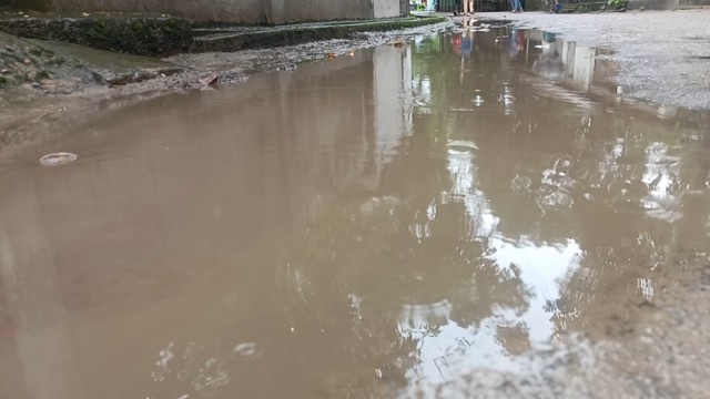 Students and pedestrians wade through knee-deep water on a flooded road in Sabuzpara, Chilmari, following overnight rain and poor drainage. Photo: V7N