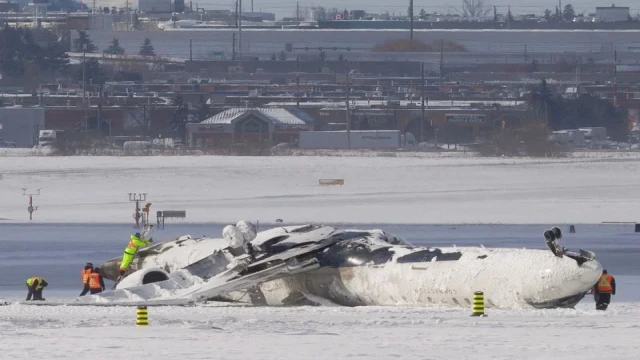 Investigators examine the wreckage of the Delta CRJ900 at Toronto Pearson Airport.