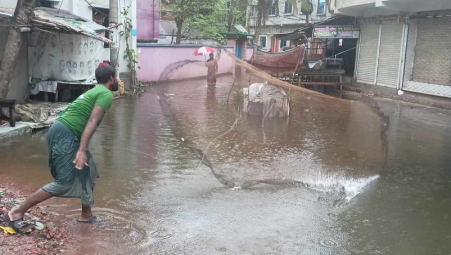 Due to heavy rains in Khulna, roads, houses, and schools have been submerged by floodwaters. The rising waters have led to an influx of fish on the streets, prompting many residents to catch them using nets. Photo: V7N