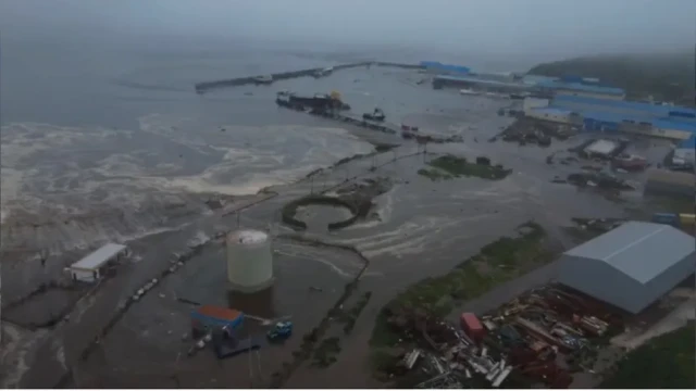 Aerial view shows tsunami waves flooding Severo-Kurilsk after 8.8 quake off Kamchatka, submerging buildings and sweeping vessels.
