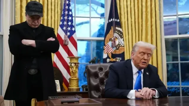 Elon Musk, wearing a black MAGA hat, joins President Trump in the Oval Office to discuss the importance of reducing federal spending and reforming the federal bureaucracy.