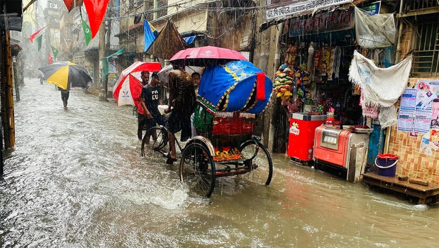 A man pulls a rickshaw as people trudge through a waterlogged road amid rain in Wari, Dhaka, on Friday.